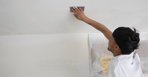 A professional painter sanding the ceiling of a freshly painted garage_That 1 Painter Arlington Alexandria