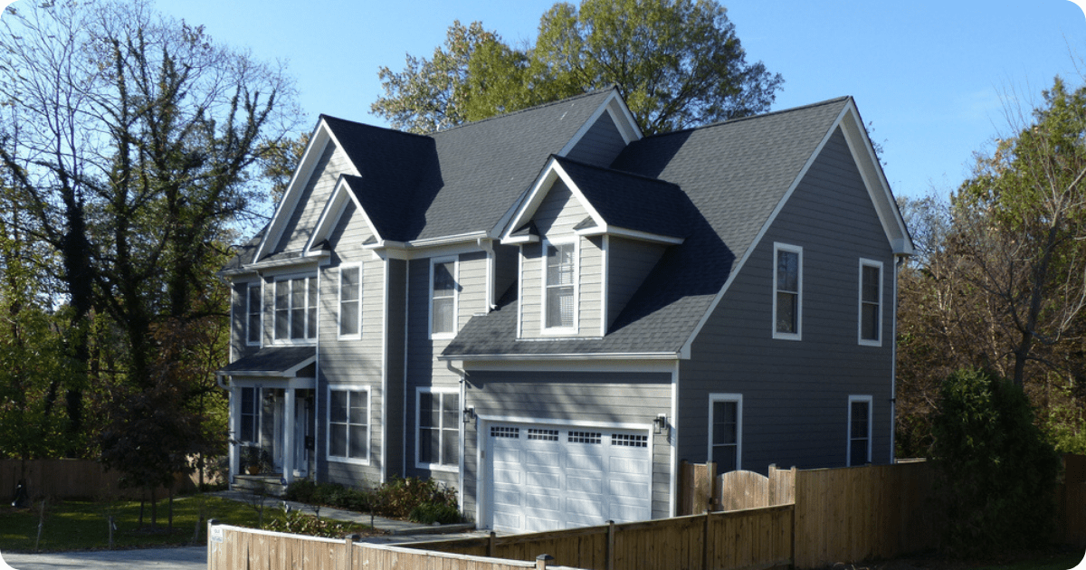 Exterior painting in _arlington-alexandria of a modern two-story gray house with multiple gables, white trim, and a double garage door surrounded by mature trees by that 1 painter.