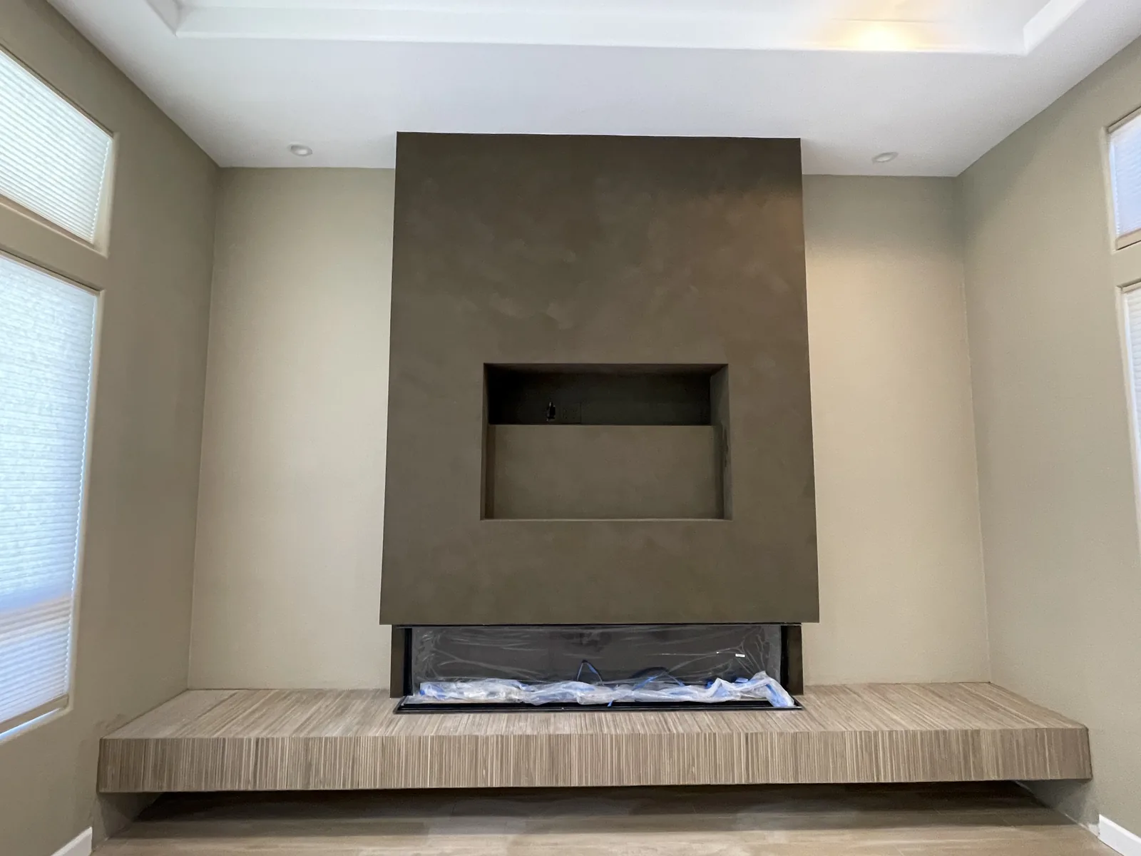 Taupe limewash fireplace surround with an inset display niche above a floating wood hearth bench applied by That 1 Painter Peoria-Glendale