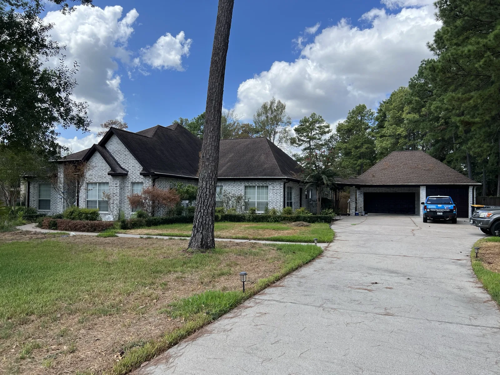 White limewashed brick home exterior with dark roof and mature trees applied by That 1 Painter Peoria-Glendale