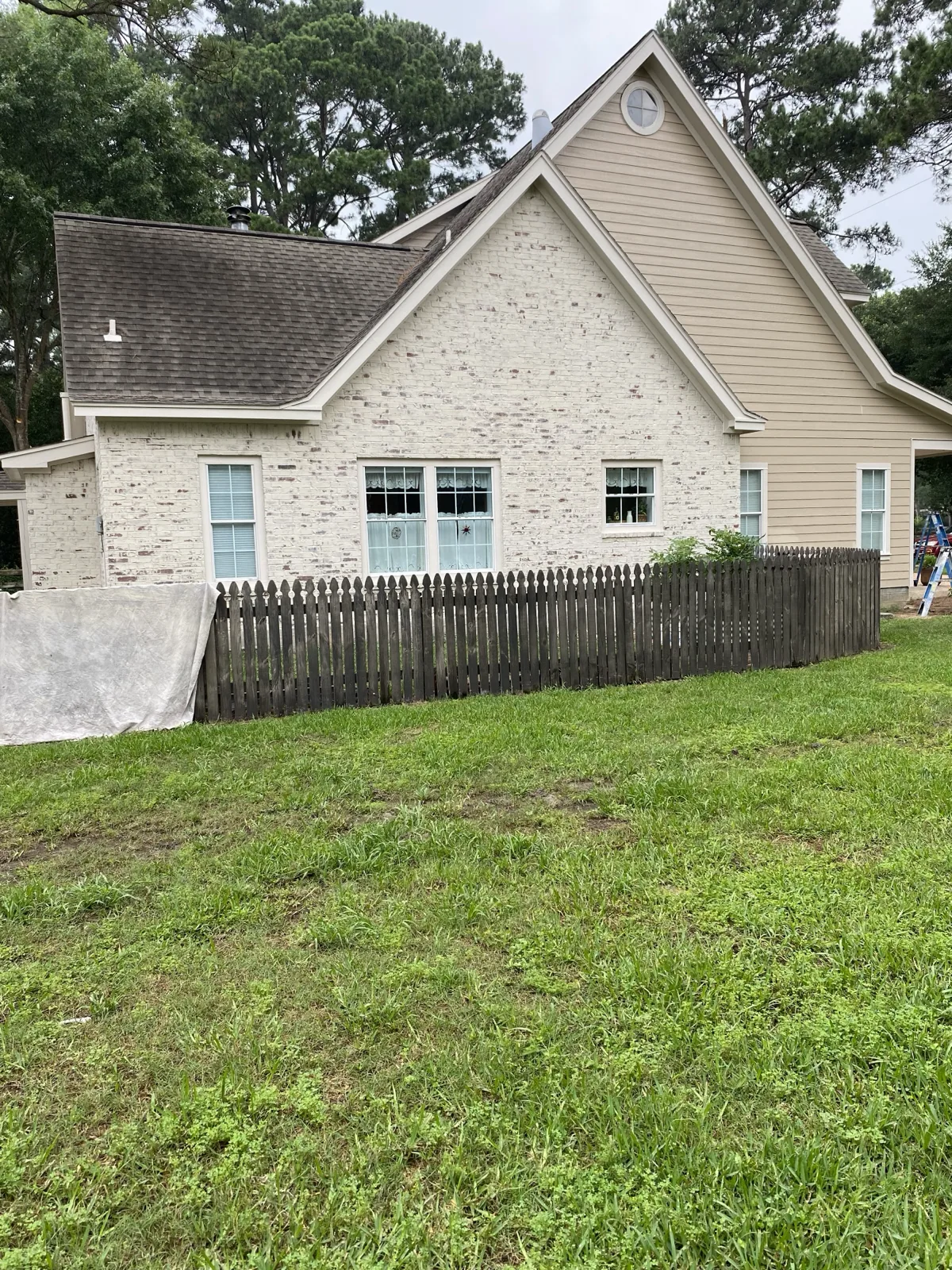 Side elevation of a limewashed brick home with white finish and garden fence applied by That 1 Painter Peoria-Glendale