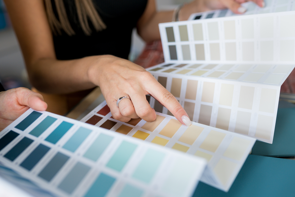 women with a large brochure with different interior paint colors in minneapolis swatches