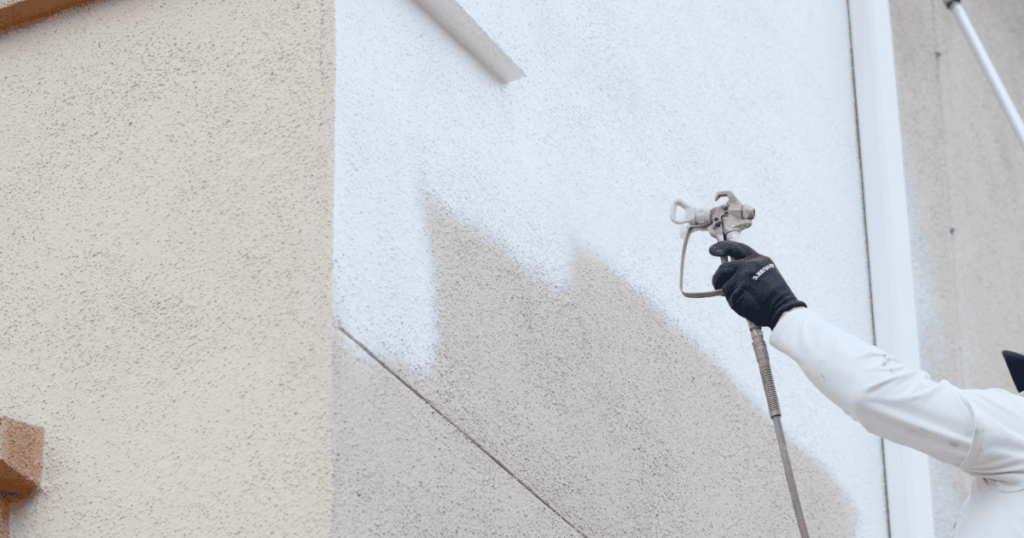 White home exterior being spray painted by professional painters in Bloomington, MN