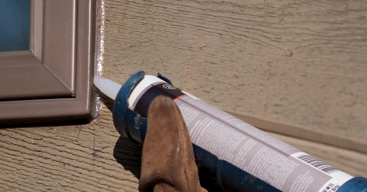 Freshly tooled caulk around an exterior window frame on lap siding