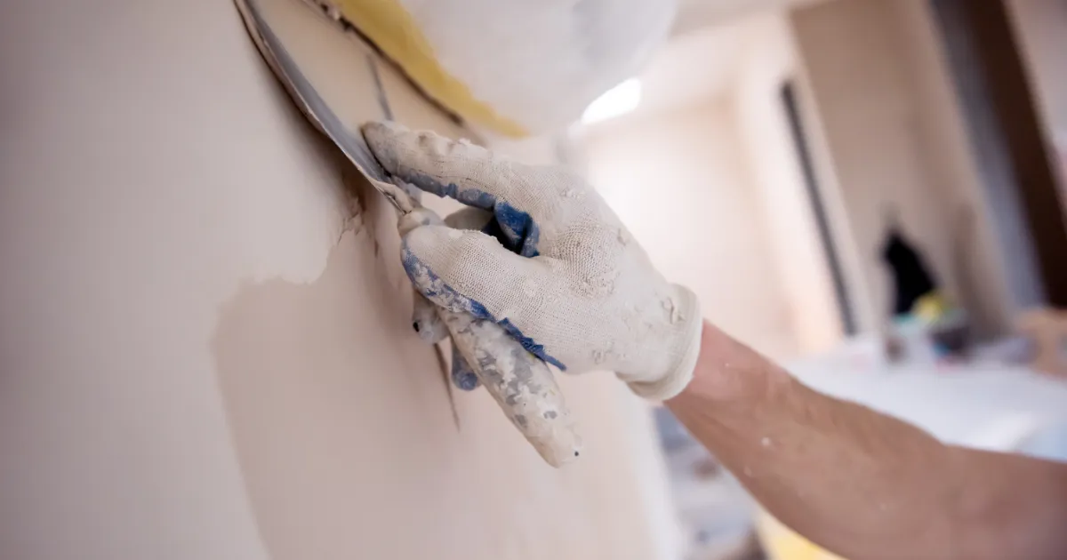 Close-up of hand smoothing drywall compound
