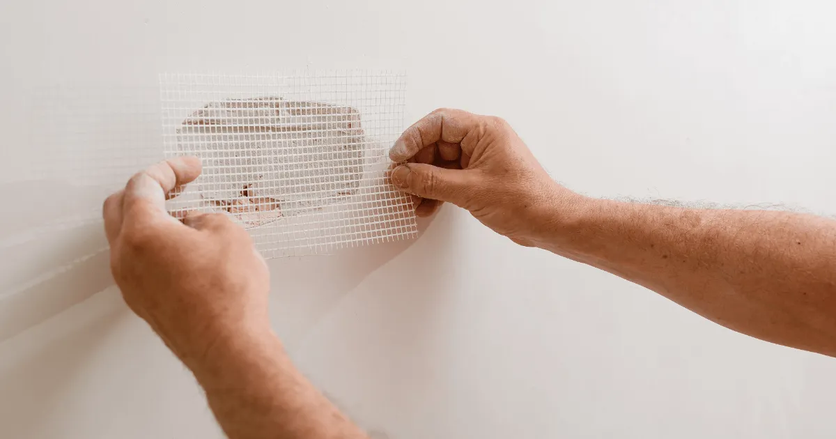 Applying mesh tape patch to drywall hole repair