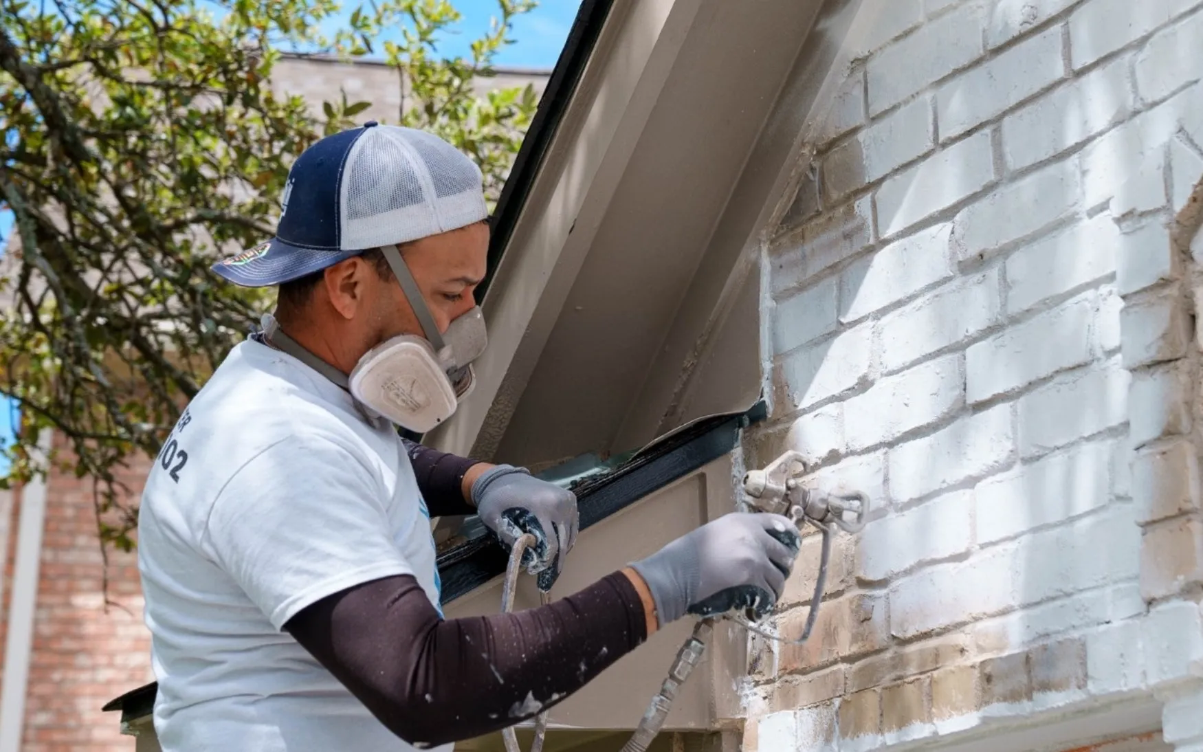 Professional painter spraying a fresh exterior finish coat on residential siding after thorough prep