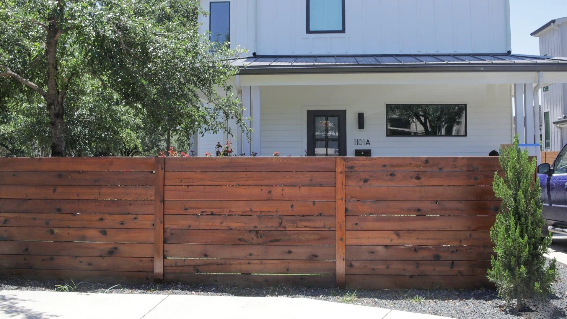 Homeowner inspecting freshly stained backyard wood fence during final walkthrough
