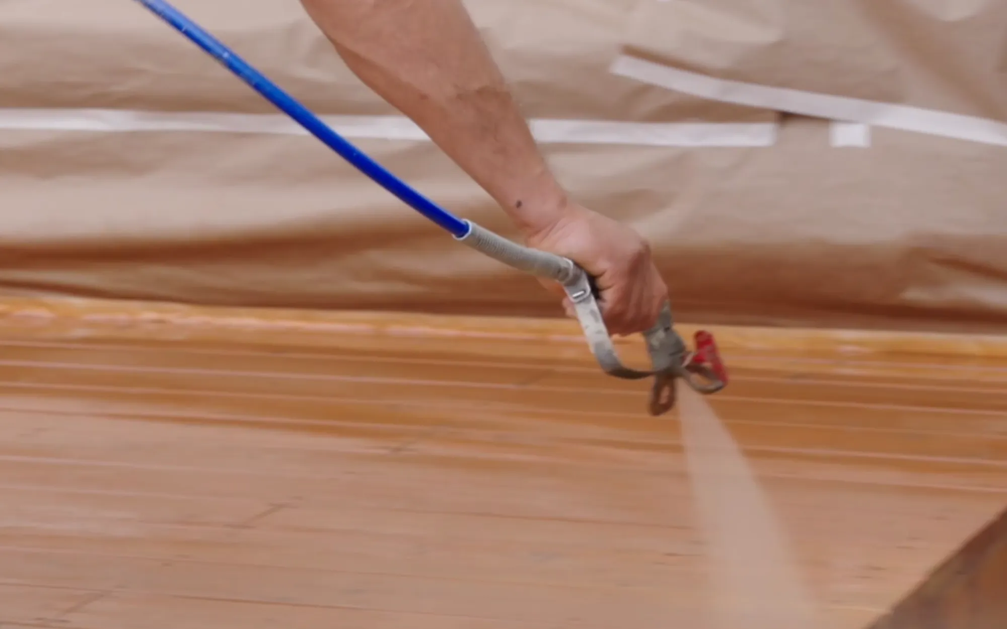 Professional applying semi-transparent stain to a freshly prepped wood deck