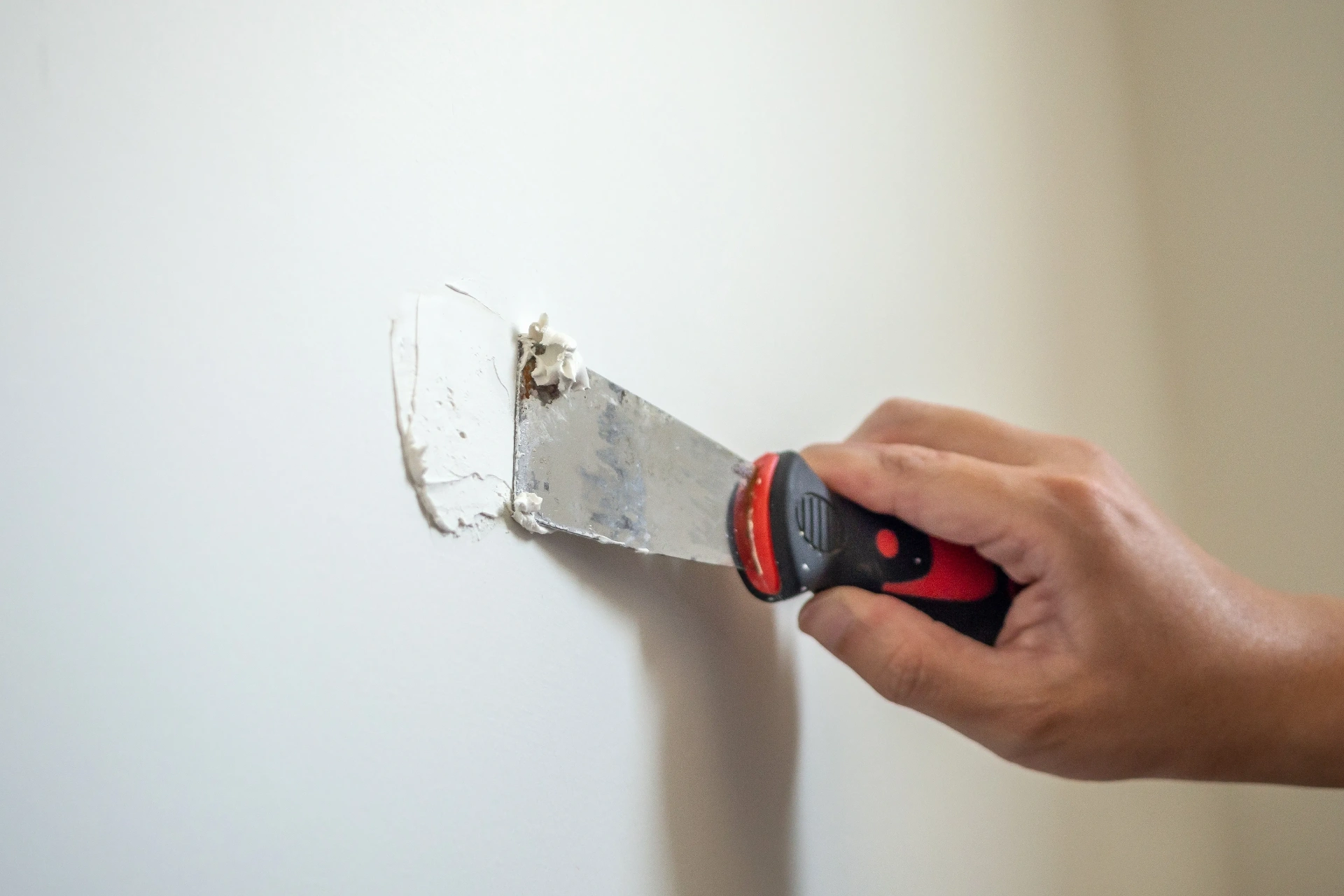 Painter spackling a small drywall patch during sale-prep work
