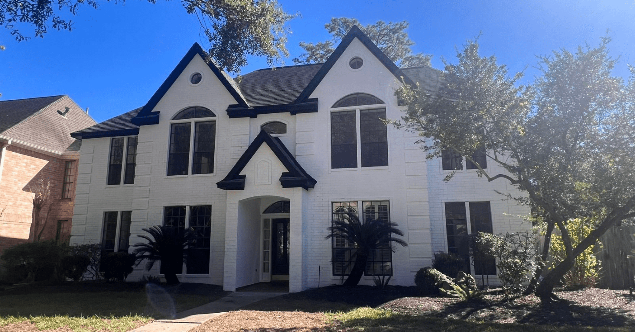 a brick home painted white with black trim by professional painters at That 1 Painter Bellaire