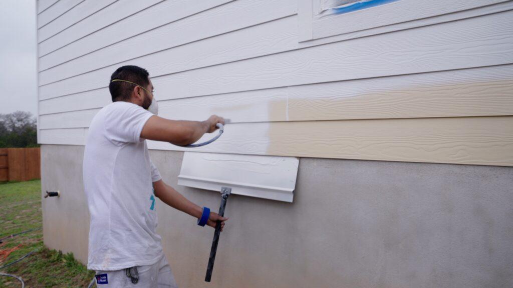 Painters spray painting the exterior of a house white - That 1 Painter East Austin Bastrop