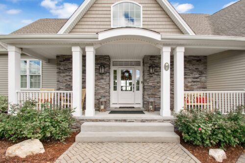 Exterior of a tan and natural stone house with white trim all finished by professional painters in Longview, Tx.