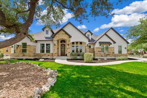 Large modern stone house with light siding and dark accents all painted as part of a residential painting projects by professional painters in Bullard.