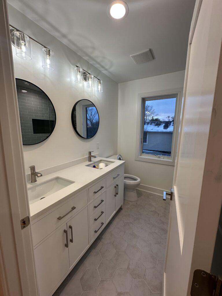 White Bathroom with round mirrors and window showing the dos and don'ts of that 1 painter essex