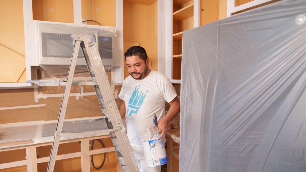 A painter with That 1 Painter Eugene painting kitchen cabinets for color selection.