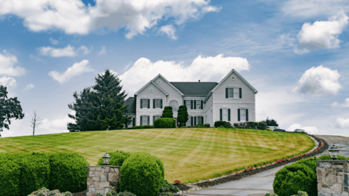 Exterior painting of a large white house with windows with brown trim completed by professional painters in Tysons, Virginia.