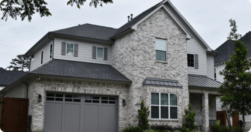 Exterior of a new house with light gray brick, white siding, and dark accents painted by professional painters in Burnet.