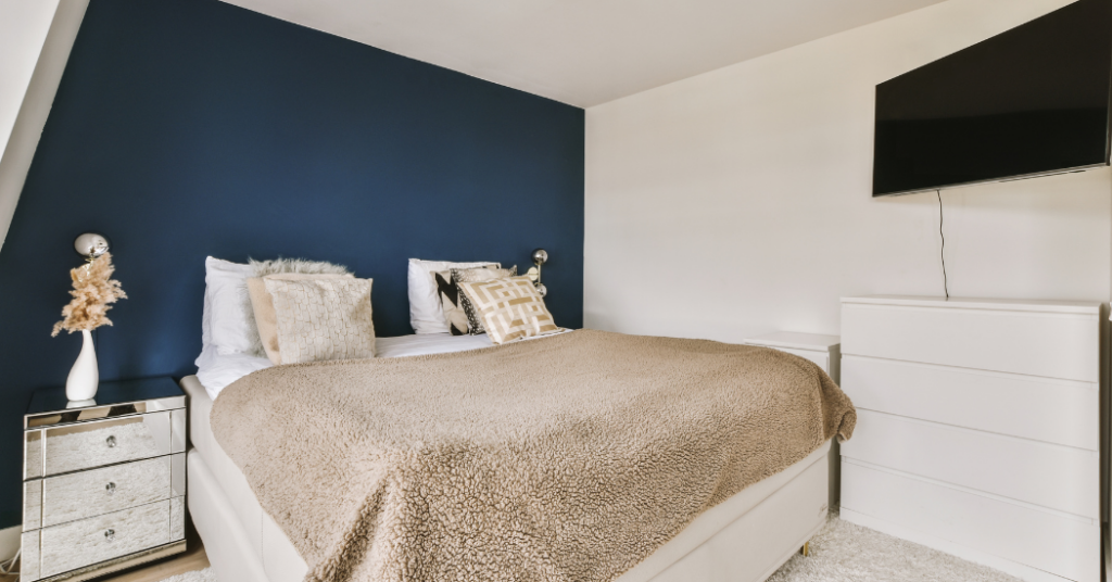 A master bedroom with a blue accent wall that was freshly painted by That 1 Painter