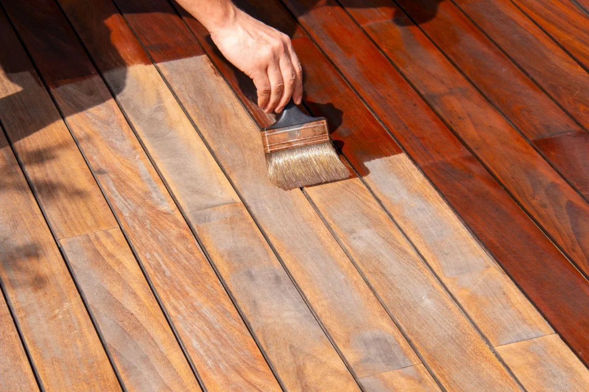 Brush applying wood stain to deck boards
