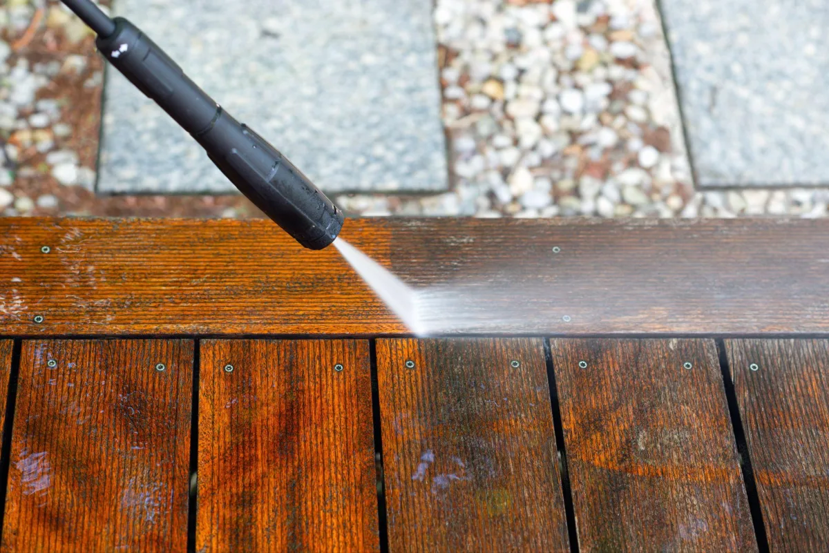 Pressure washing a wooden deck surface before staining