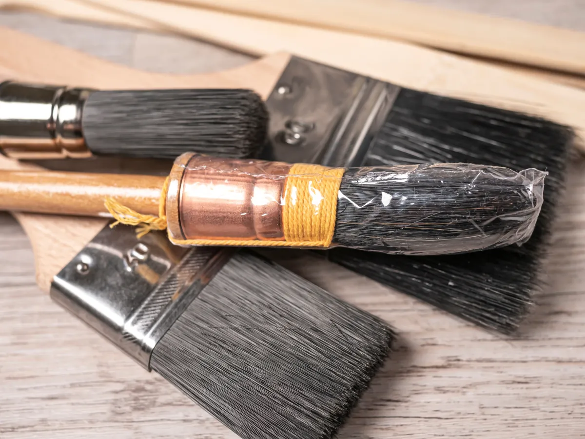 Clean flat paint brushes of different sizes laid on a wooden floor