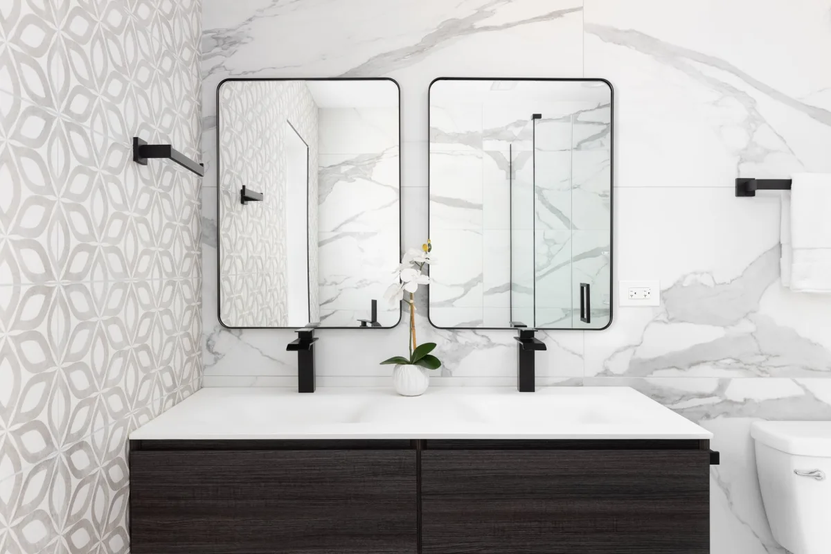 Modern bathroom with a dark wood double vanity, black-framed mirrors and white marble tile