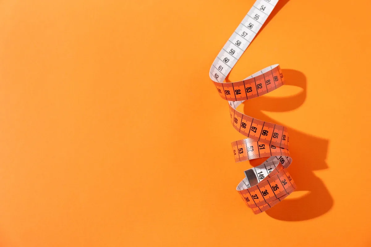 Measuring tape coiled on an orange background