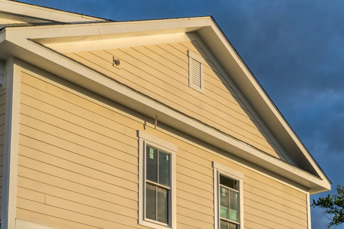 Fiber cement lap siding and trim on a home gable against a dark sky