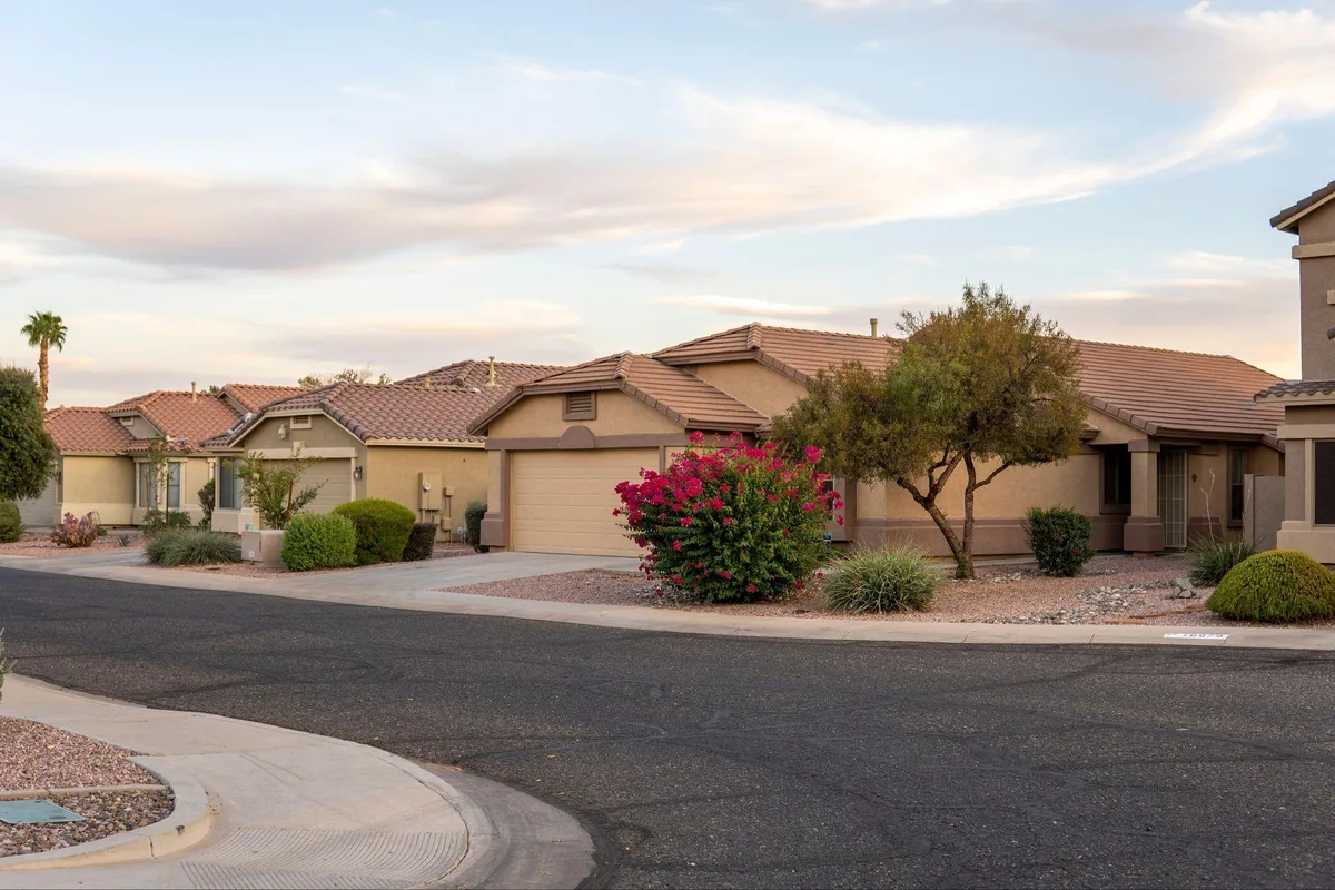 Row of tan stucco homes with tile roofs along a desert neighborhood street at dusk