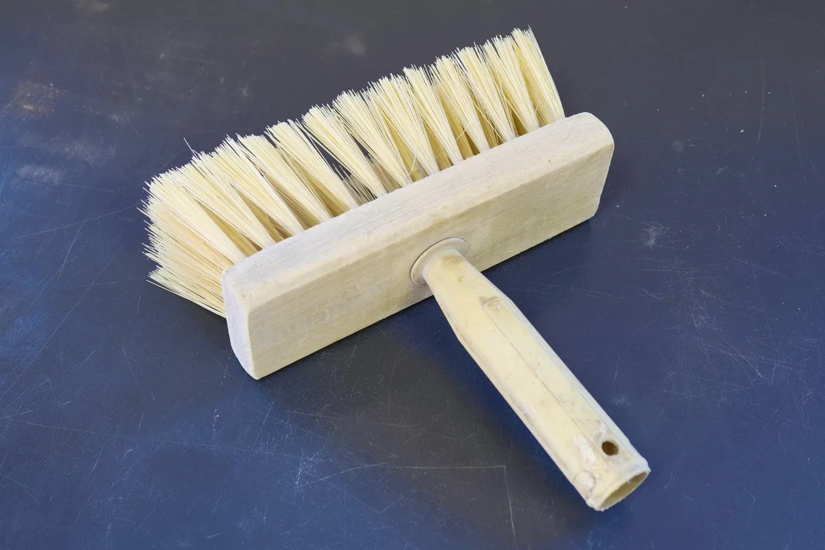 Wooden block masonry brush with long stiff bristles used for applying limewash