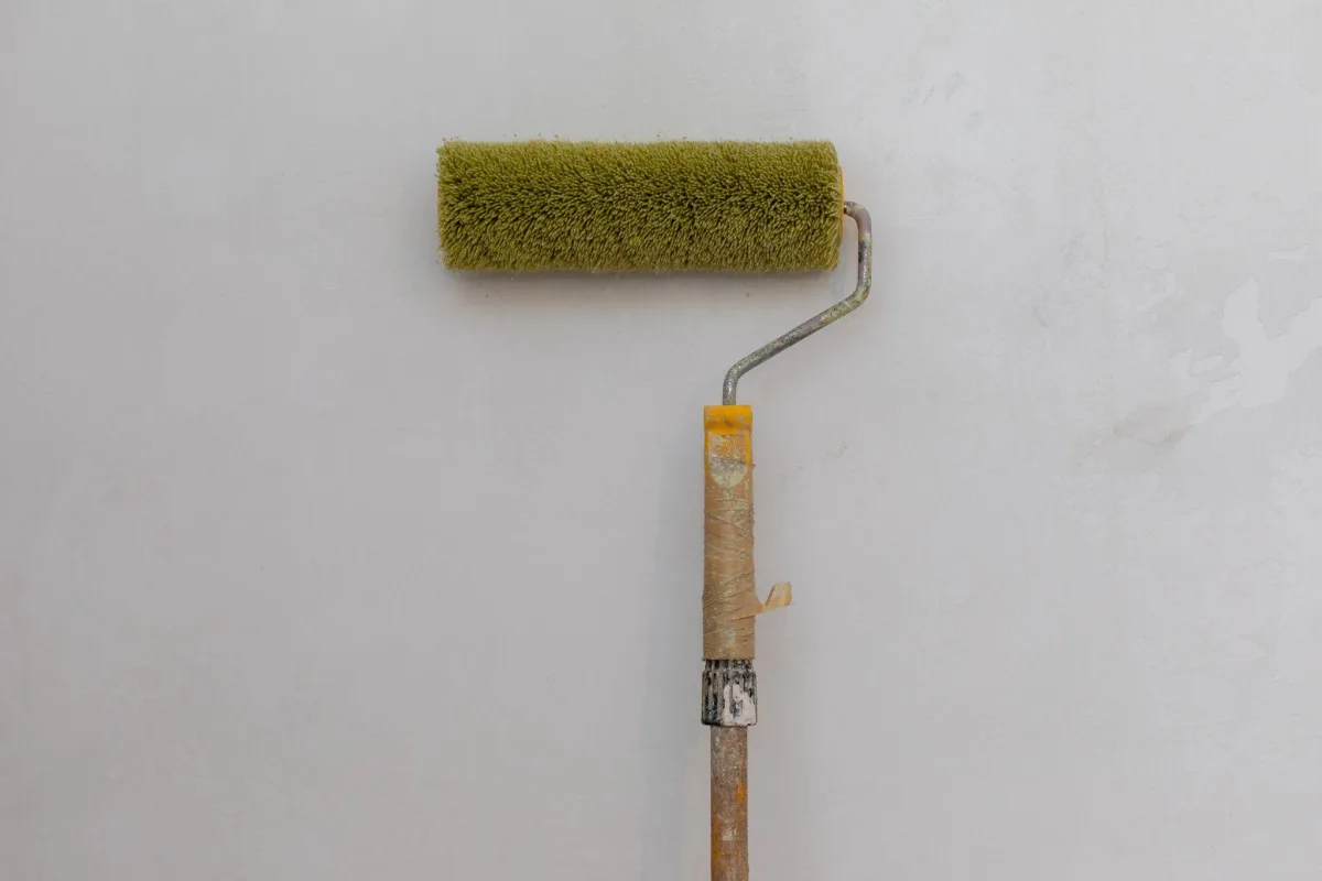 Long nap paint roller on an extension pole against a textured wall