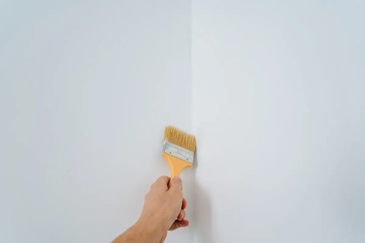 Small paintbrush touching up paint along a white wall