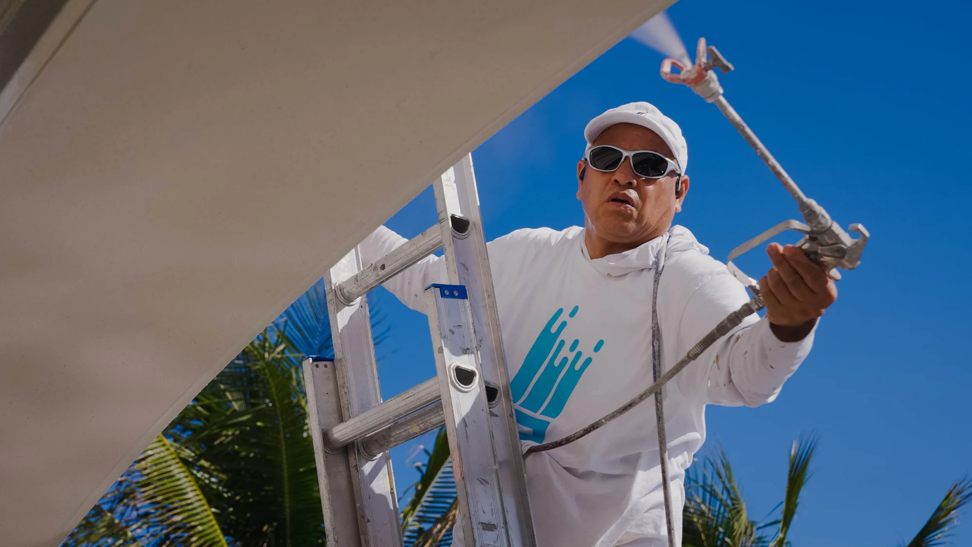 That 1 Painter St. Petersburg painter spraying exterior soffits and trim from a ladder in St. Petersburg, FL