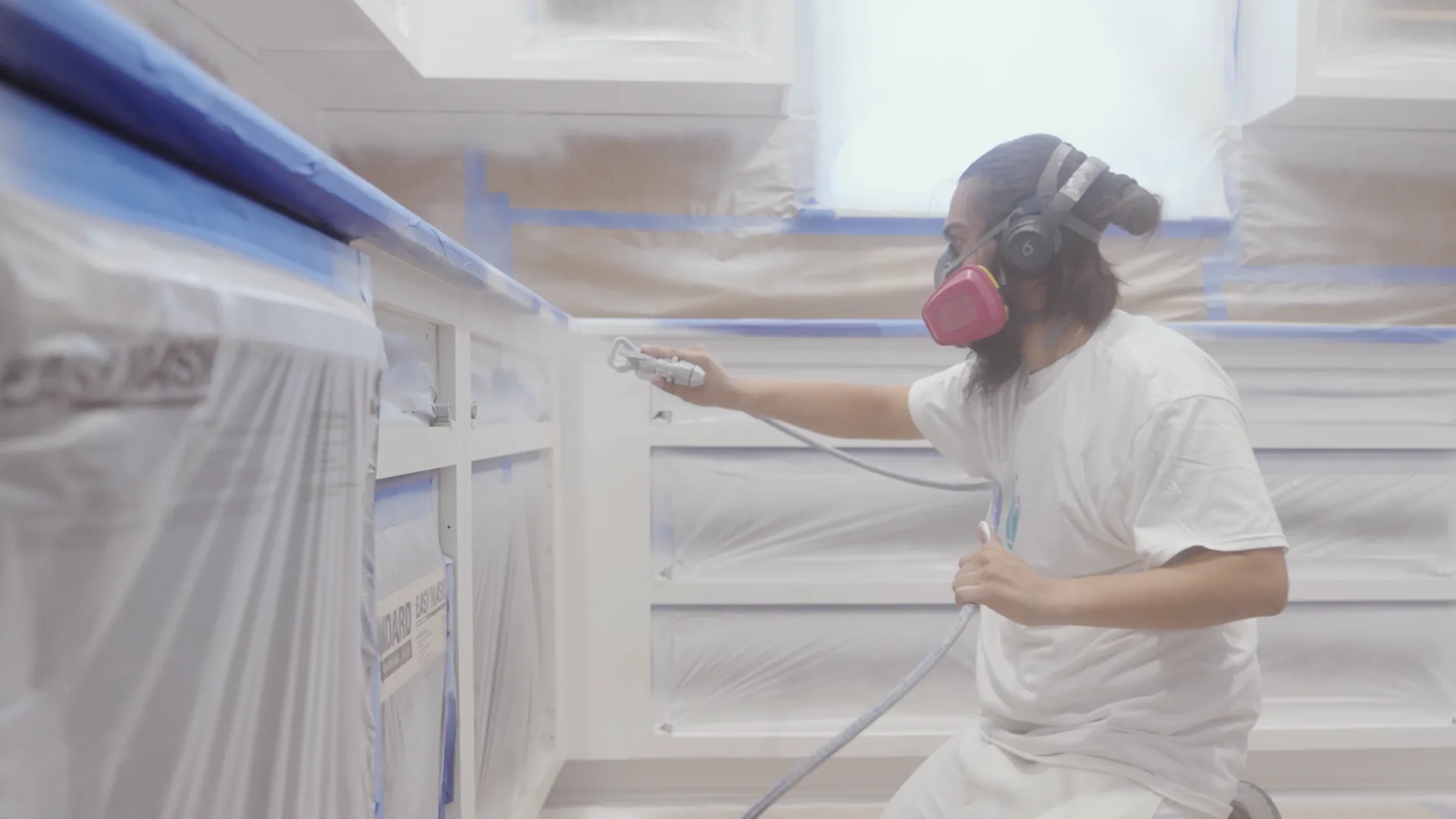 That 1 Painter Tampa Bay painter spraying kitchen cabinets in a fully masked kitchen in Tampa, FL