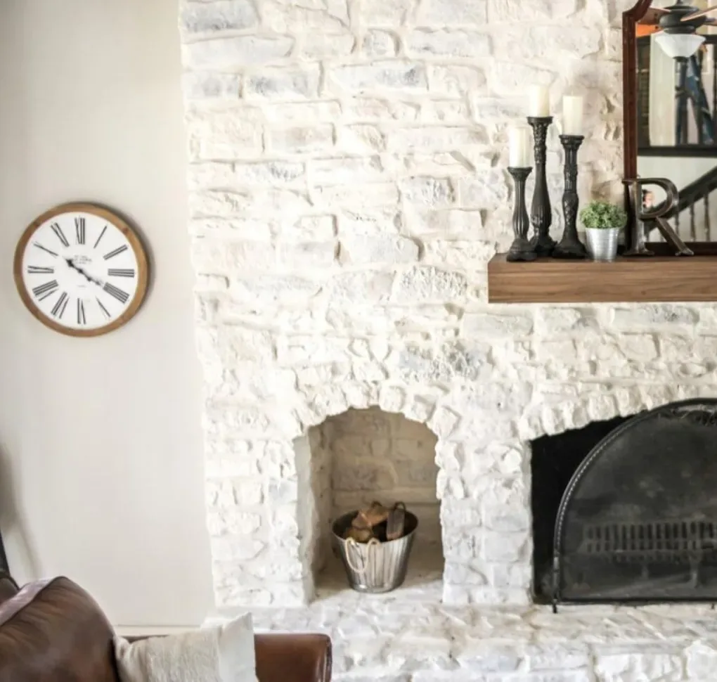 Painter applying limewash to a brick fireplace wall inside an Allison Park - PA home