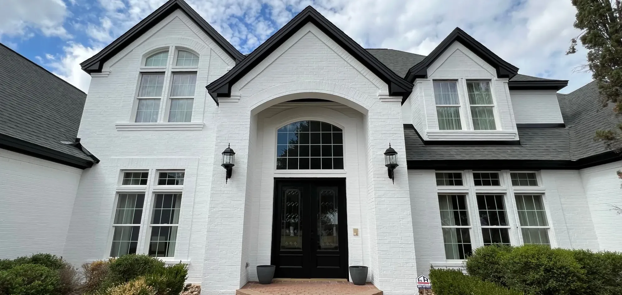 Front entry of a limewashed brick home with steep gables in Aspinwall, PA