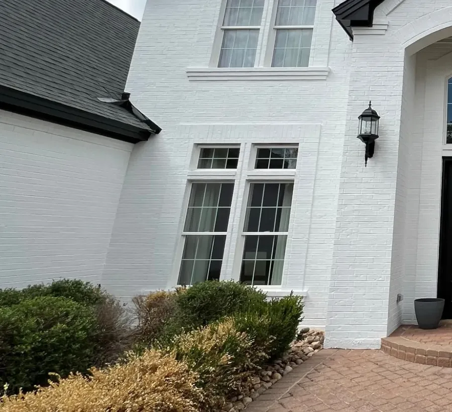 Limewash in Fox Chapel - PA being applied to a brick garden wall beside a landscaped driveway