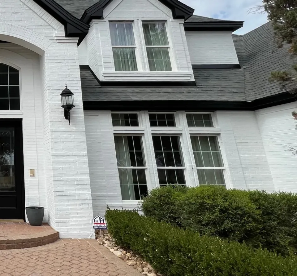 Limewash in Oakmont - PA being applied to an exterior brick wall beside trimmed landscaping
