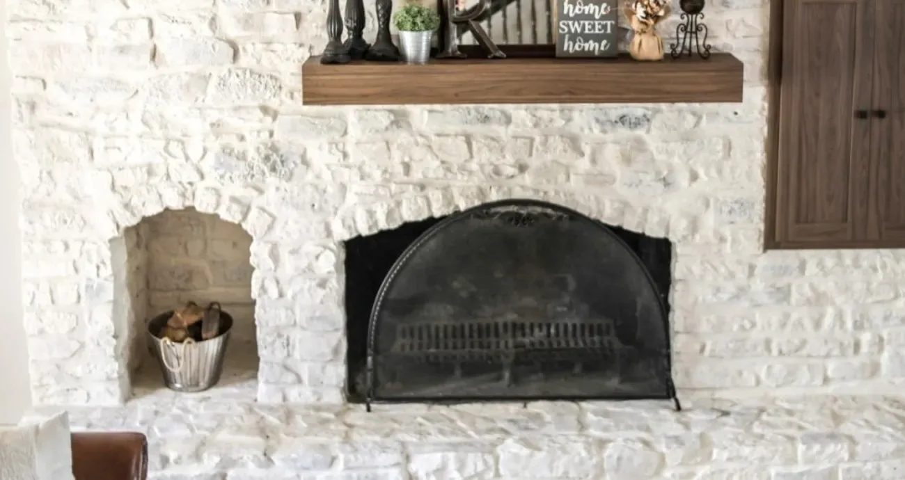 Painter brushing limewash across an Oakmont - PA brick fireplace for a softer aged finish