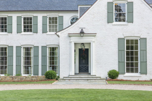 Exterior of a white brick house with large green shutters painted by painters in West Knoxville