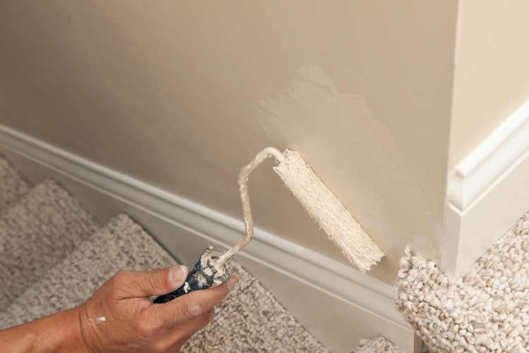 A painter applying fresh interior paint to a living room wall during a winter home refresh in Braselton, Georgia.
