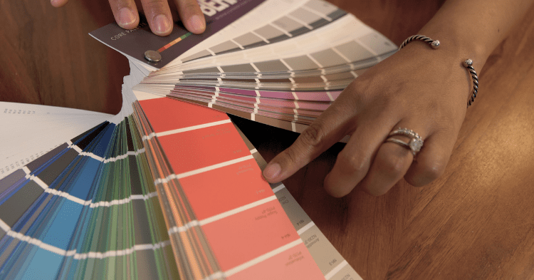 Close up of a woman picking out a coral color for her cabinets on a swatch fan deck_That 1 Painter Loudoun