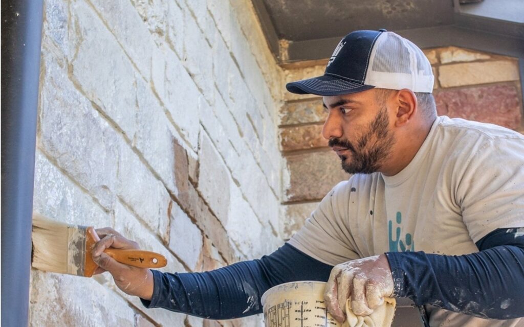 professional using limewash brick paint alternatives on a brick house