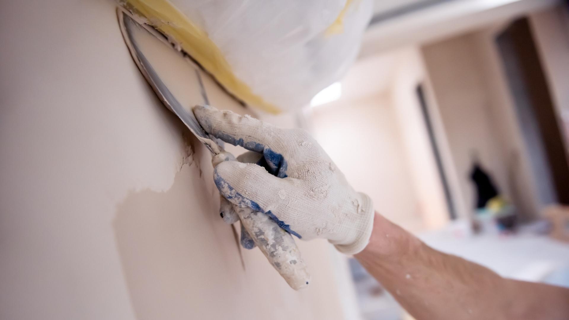 Professional painter using a scraper to finish a drywall repair project_that 1 painter michiana