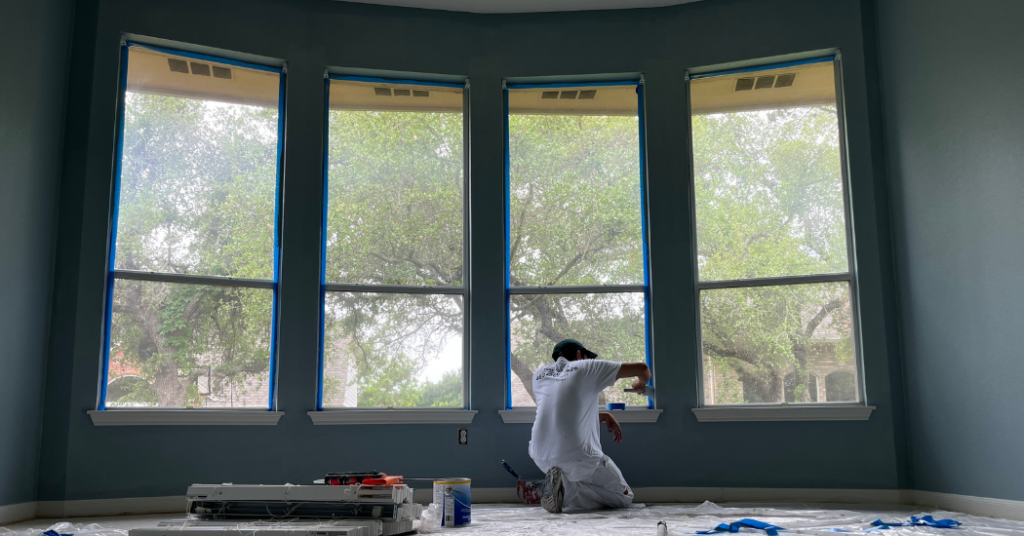 A painter in painters whites, taping up windows of a residential property before painting - That 1 Painter  Naples.