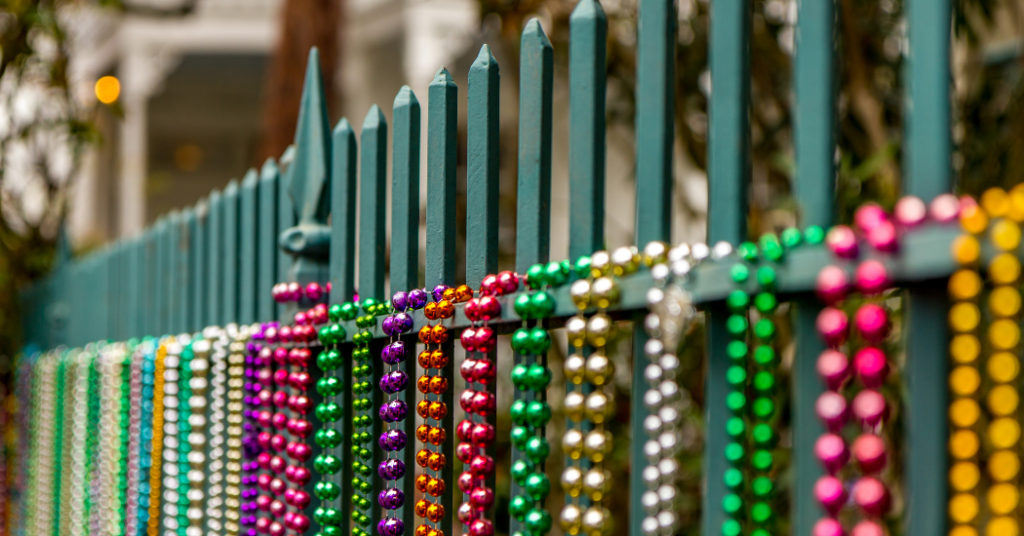 Colorful necklaces hanging off of a rod iron fence new New Orleans Businesses promoting commercial painting - That 1 Painter New Orleans