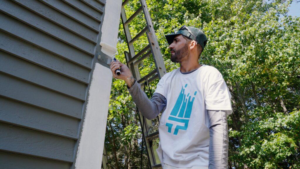A painter from That 1 Painter New Orleans painting with moisture resistant paint on the outside of a home.