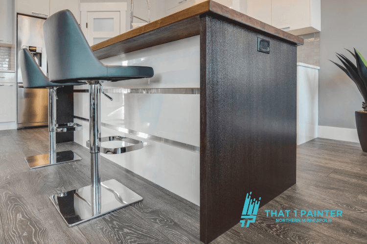 A stylish kitchen island featuring a rich wood-stained finish paired with sleek white cabinetry and polished metal bar stools. This image showcases the attention to detail and expert craftsmanship provided by That 1 Painter, trusted for their professional cabinet and interior painting services in North Minneapolis.
