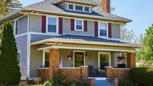 American foursquare house with brick porch pillars, blue siding, and red shutters painted by house painters in Bethany